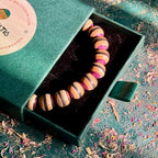 Brown, black and purple recycled skateboard wood bead bracelet in its green Baltic Dew gift box.