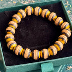 Yellow and black beaded bracelet made from recycled skateboard maple, shown from above in its box