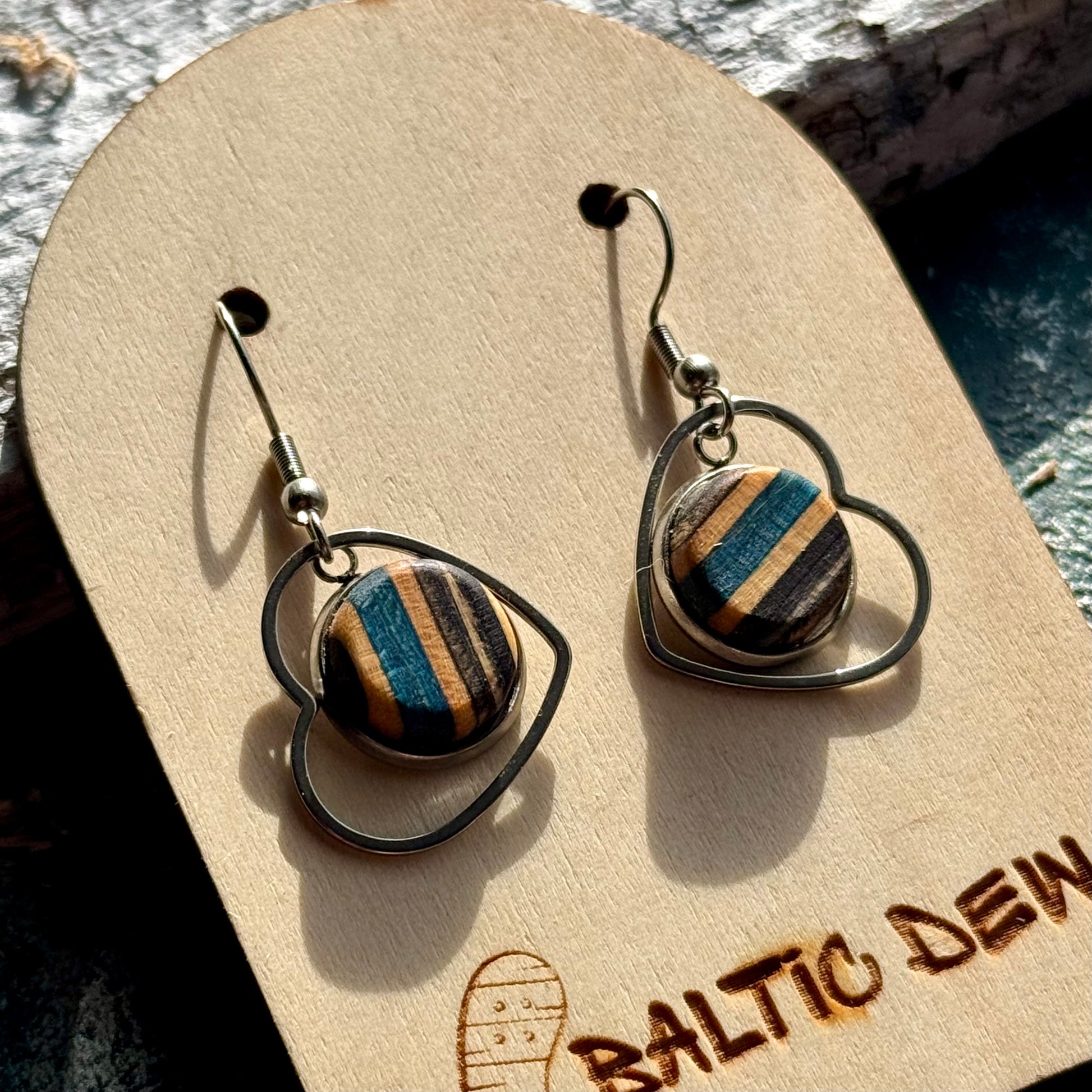 Handmade wooden earrings with blue, black and natural skateboard layers in heart frames.