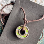 Green and blue skateboard bearing pendant with recycled maple layers on a brown waxed cotton cord.