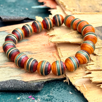 Close view of striped orange and red skateboard maple beads with green and pale maple bands, resting on a broken deck.