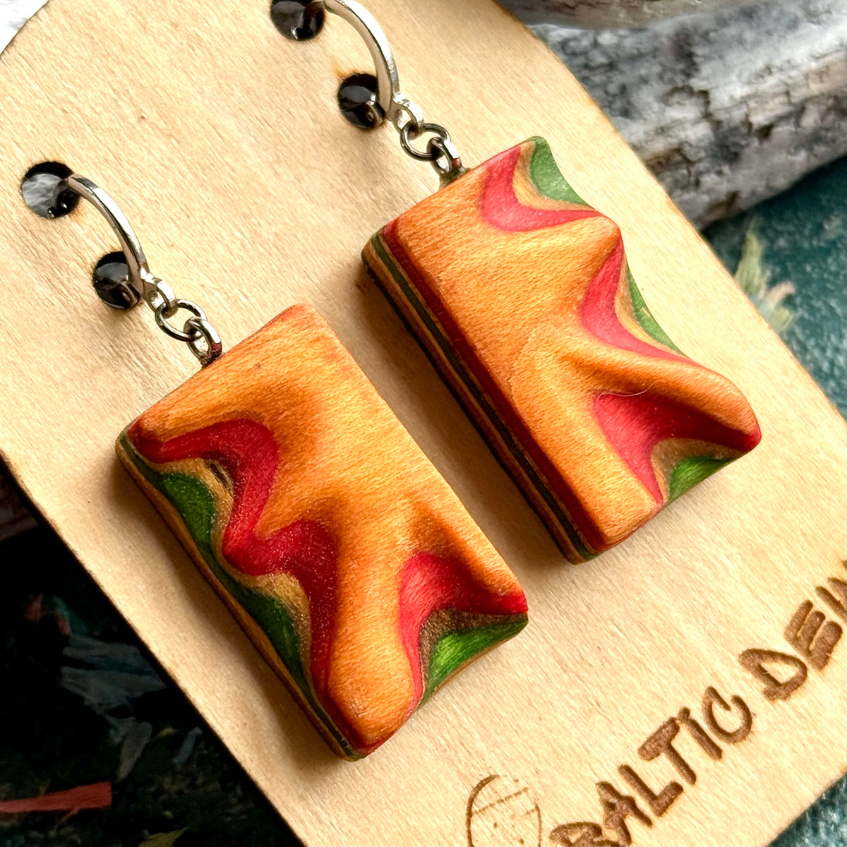 Close view of orange and red carved wave earrings showing the green layer along the edge