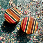Ear plugs in red, black and orange recycled maple ply, handmade by Baltic Dew.