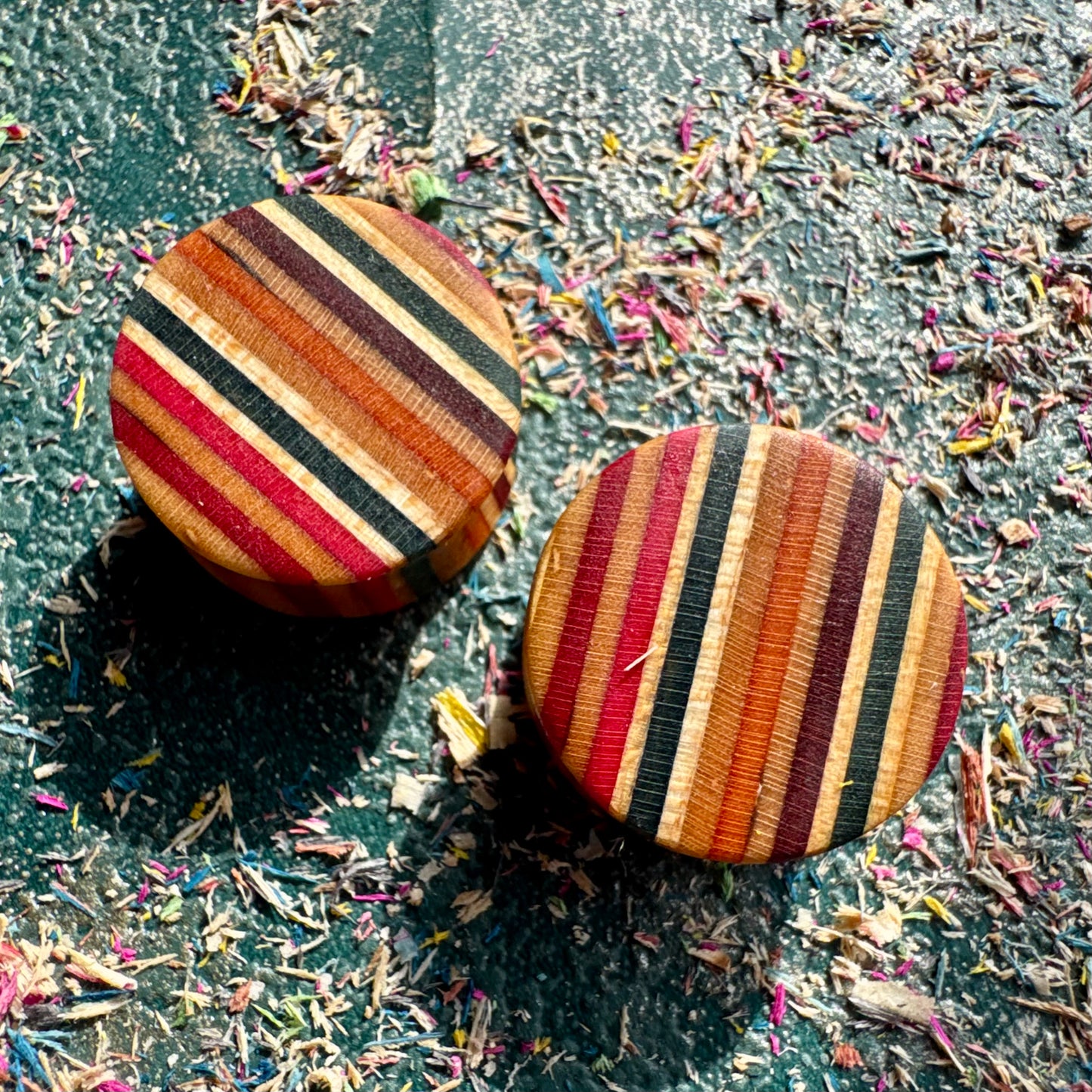 Ear plugs in red, black and orange recycled maple ply, handmade by Baltic Dew.
