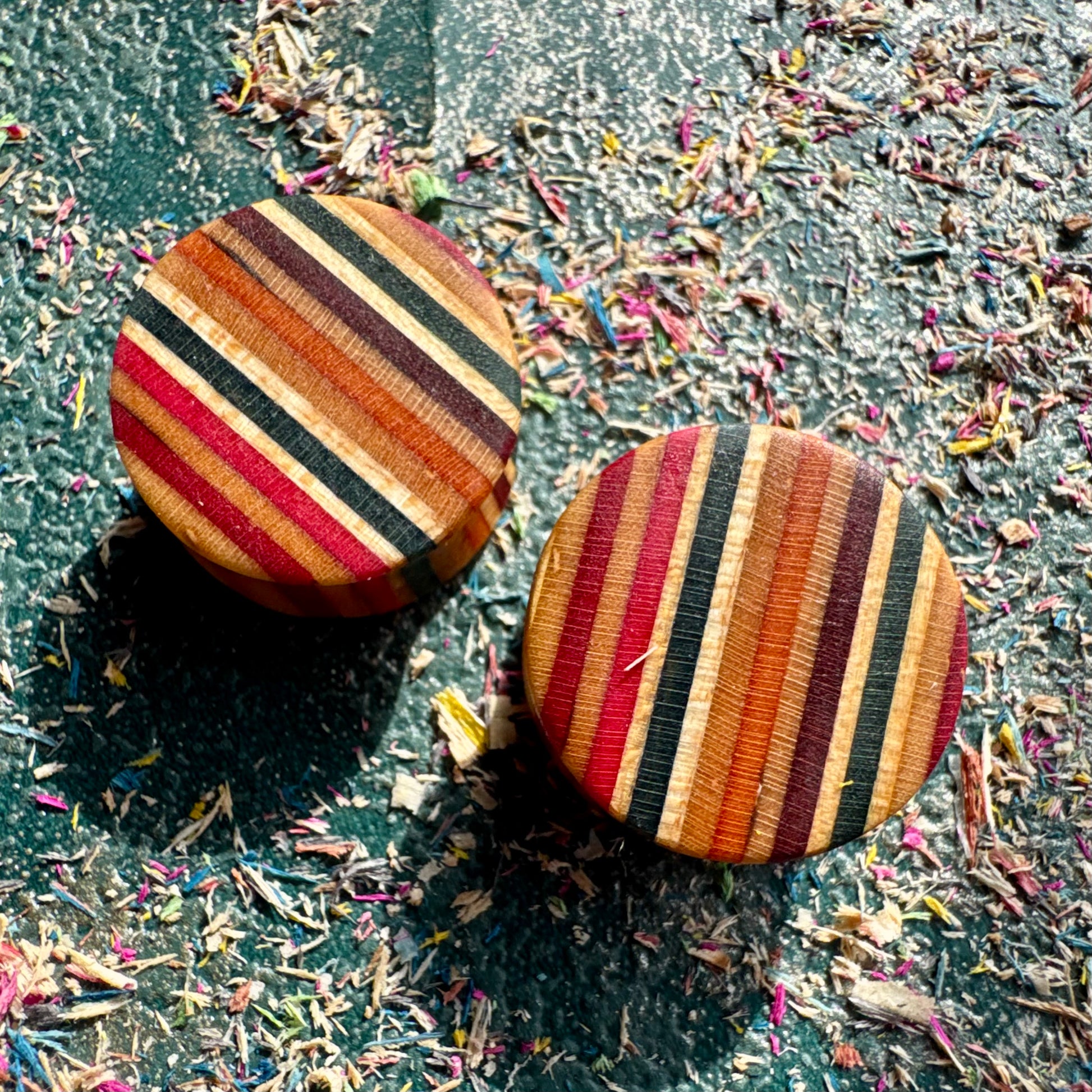 Ear plugs in red, black and orange recycled maple ply, handmade by Baltic Dew.