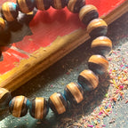 Close-up of blue and black striped beads cut from recycled skateboard maple, resting on a red and yellow deck.