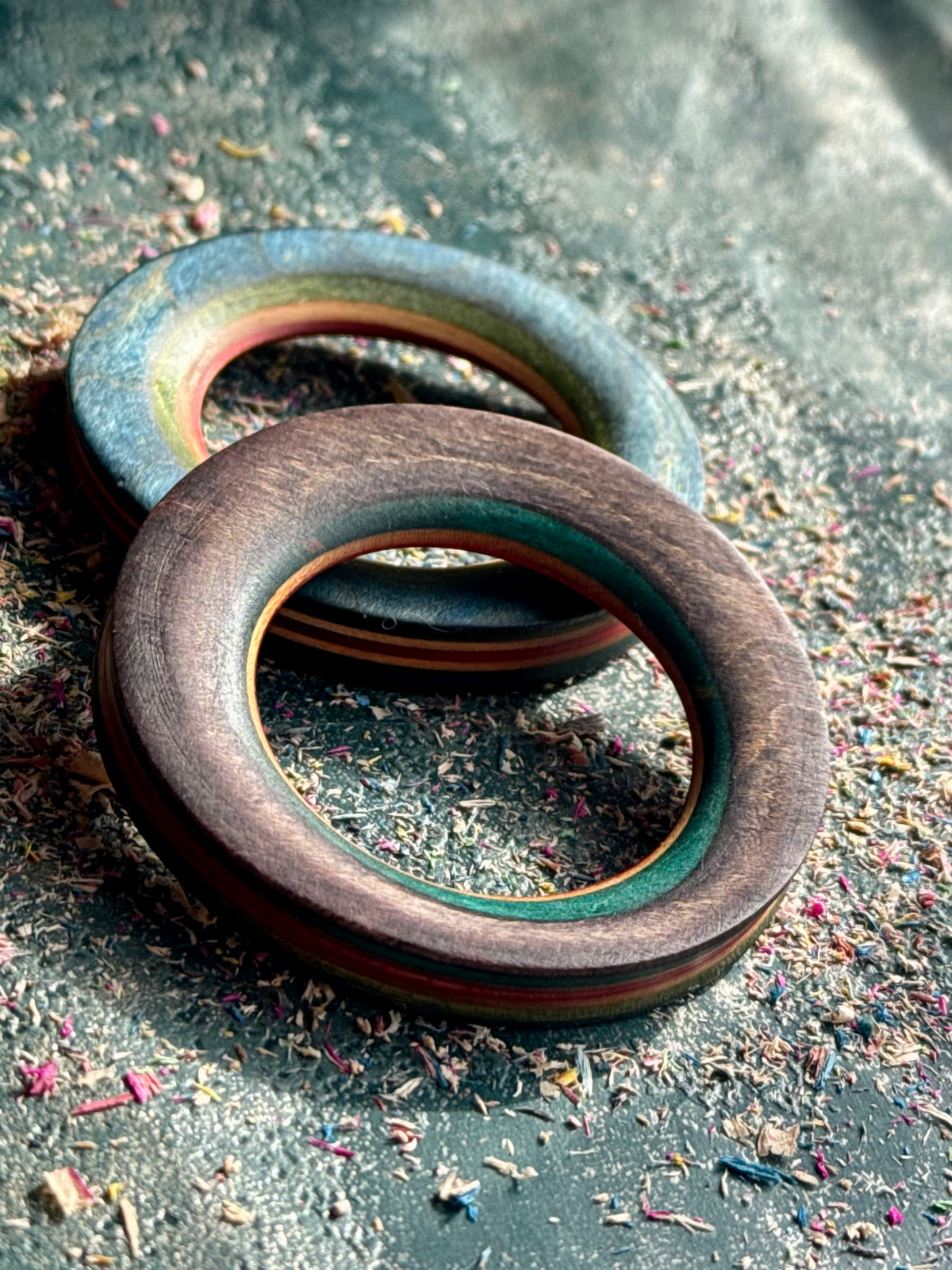 Two thick wooden tunnels in blue and brown skateboard maple, layers showing around the bore.