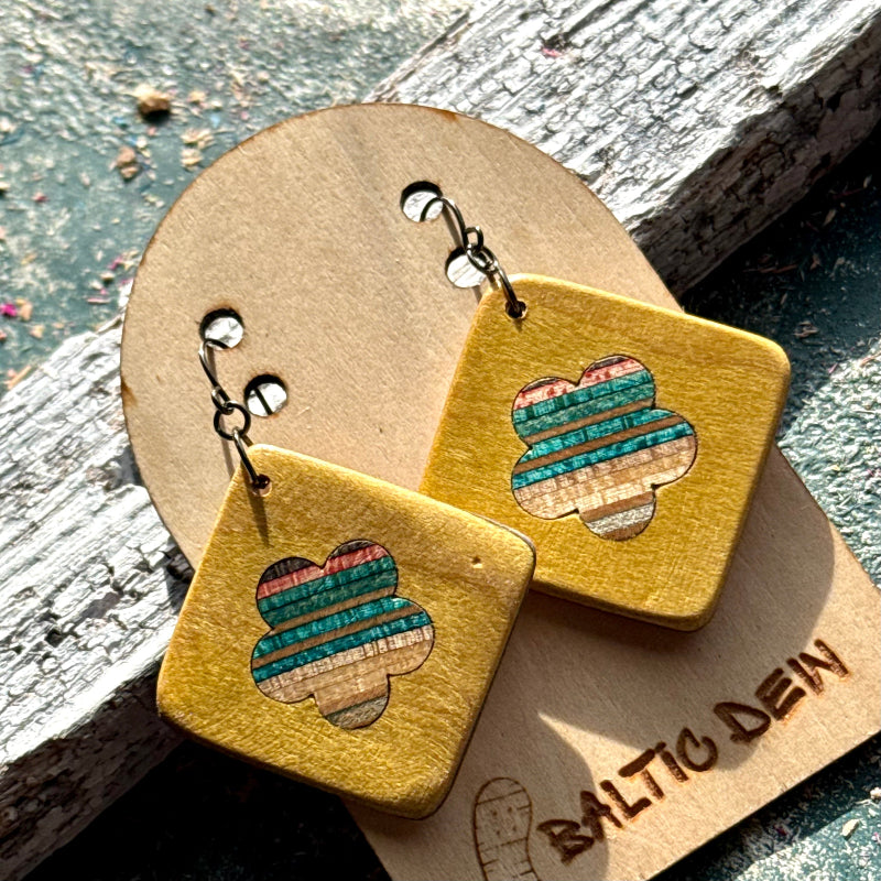 Yellow recycled skateboard square drop earrings with flower cut-outs, showing green, blue and red colour layers.