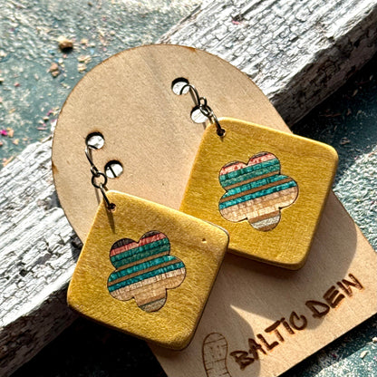 Yellow recycled skateboard square drop earrings with flower cut-outs, showing green, blue and red colour layers.
