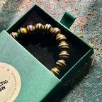 Wooden bead bracelet cut from a recycled skateboard deck, with black, yellow and green layers on every bead.