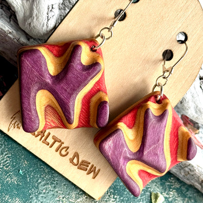 Deep carved purple and red skateboard wood earring showing the layers as contour lines