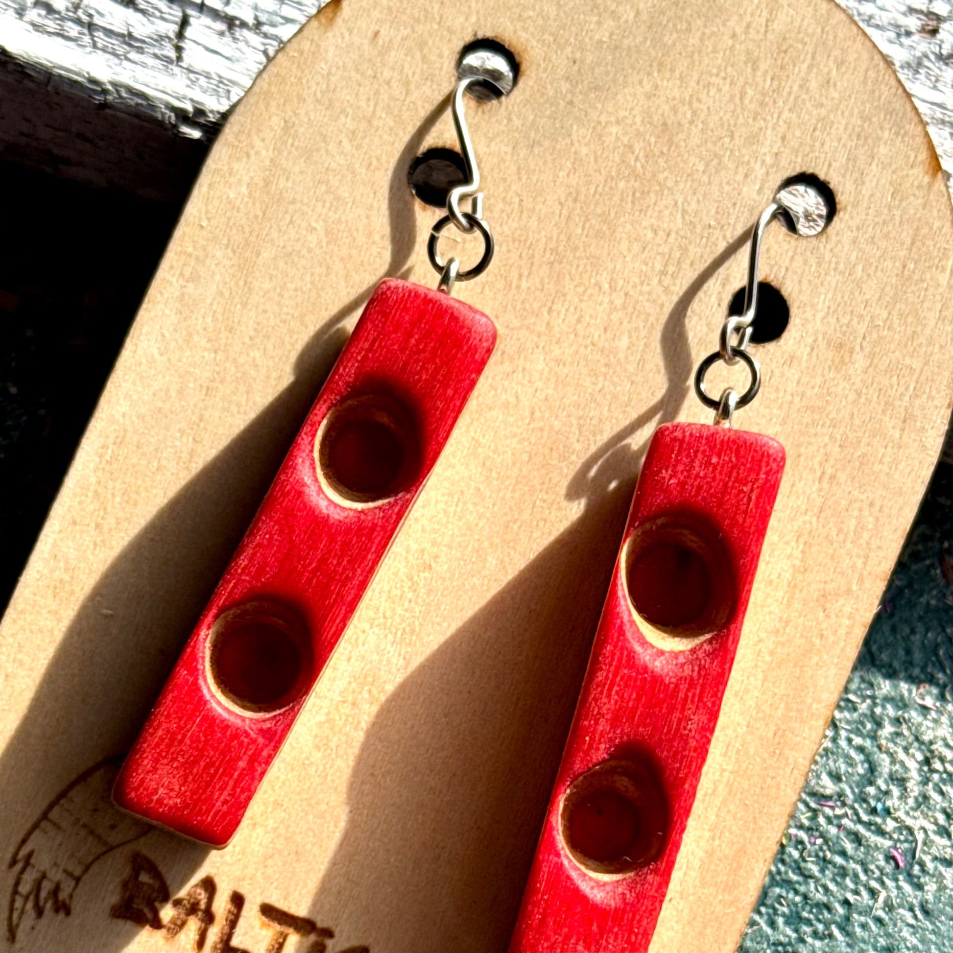 Red recycled skateboard wood bar earrings with two carved hollows in each bar, handmade by Baltic Dew