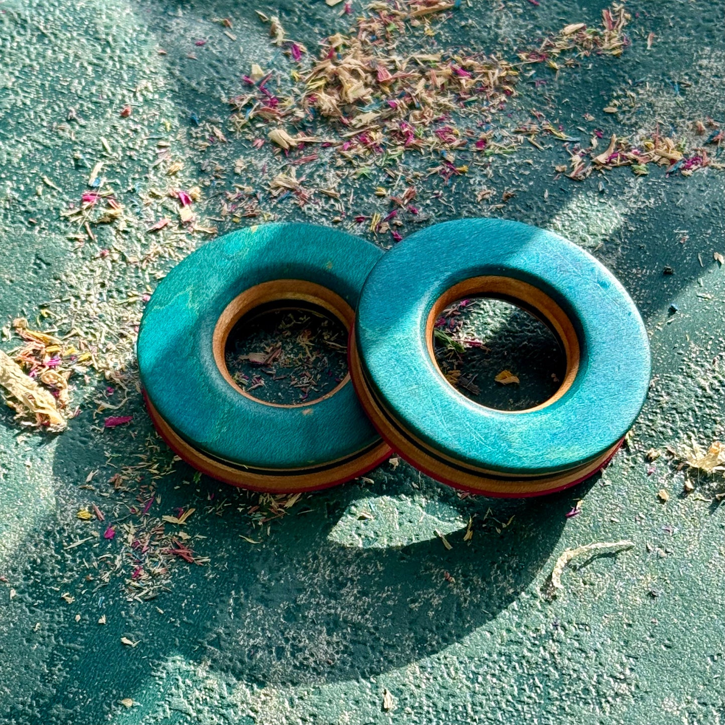 Bright blue and teal tunnels hand shaped from recycled maple ply, resting in sunlight.