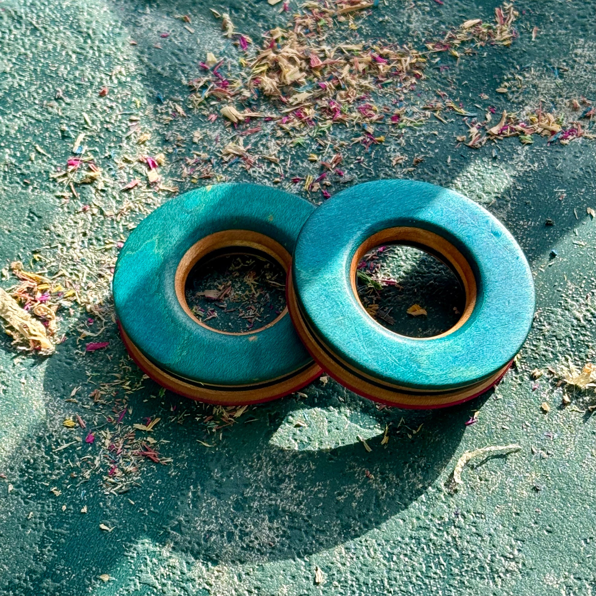 Bright blue and teal tunnels hand shaped from recycled maple ply, resting in sunlight.