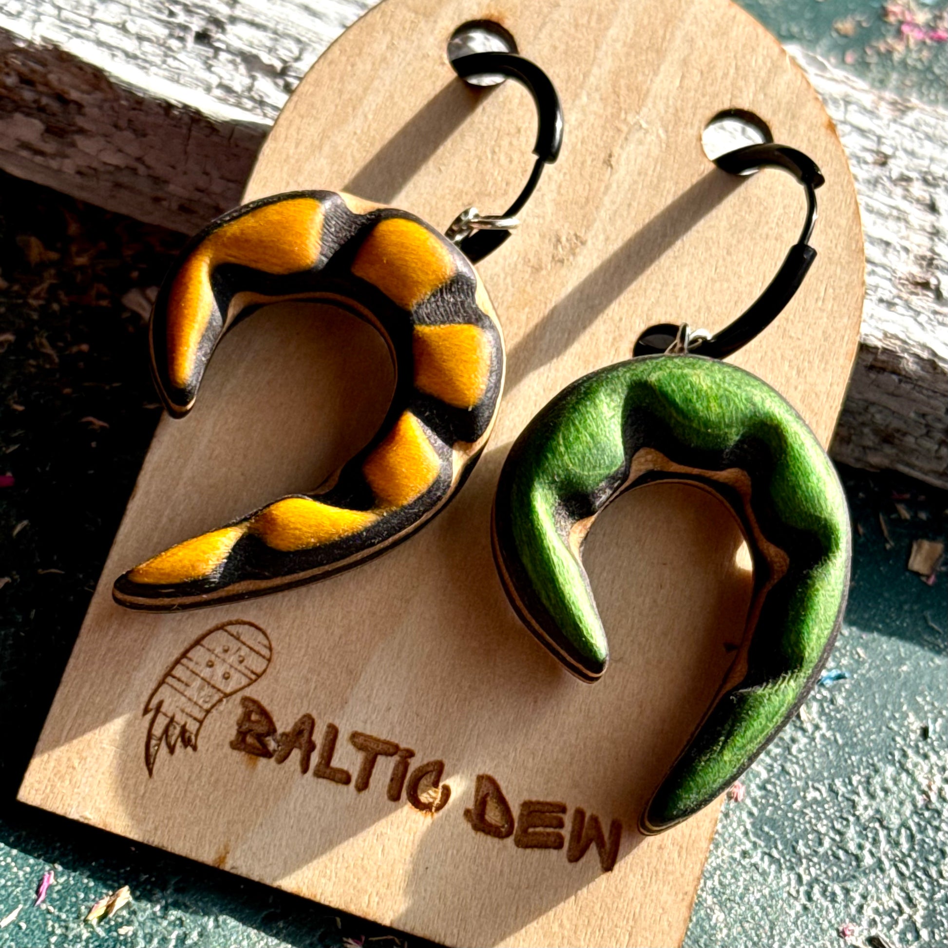Reversible recycled skateboard wood spiral earrings showing the yellow and the green side together