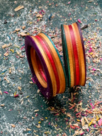 Skateboard wood tunnels stood on edge, purple rim with red, orange and green layers.