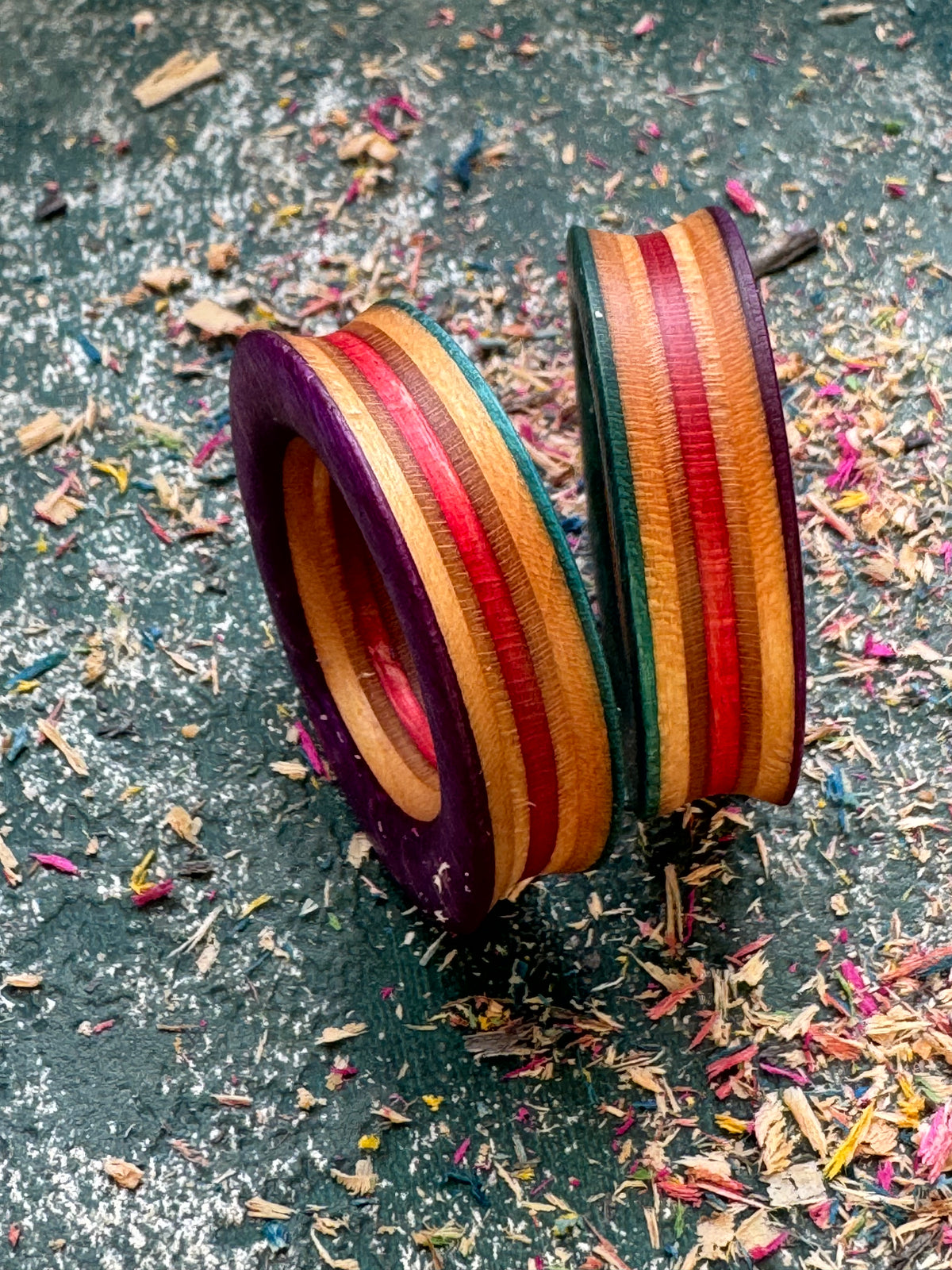 Skateboard wood tunnels stood on edge, purple rim with red, orange and green layers.