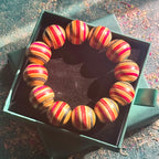 Chunky red, pink, black and teal skateboard wood bead bracelet in its green Baltic Dew gift box.
