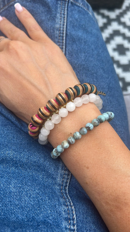 Multicolour recycled skateboard wood bead bracelet worn on the wrist, stacked with stone bead bracelets.