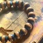 Blue and black skateboard bracelet on broken deck layers in sunlight, handmade by Baltic Dew.