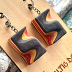 Close view of black and red carved wave earrings cut from a recycled skateboard deck