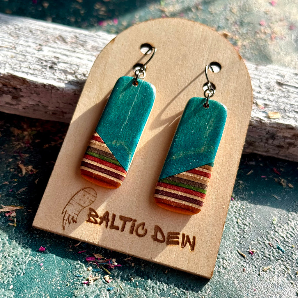 Turquoise recycled skateboard rectangle drop earrings displayed on a Baltic Dew wooden earring card.