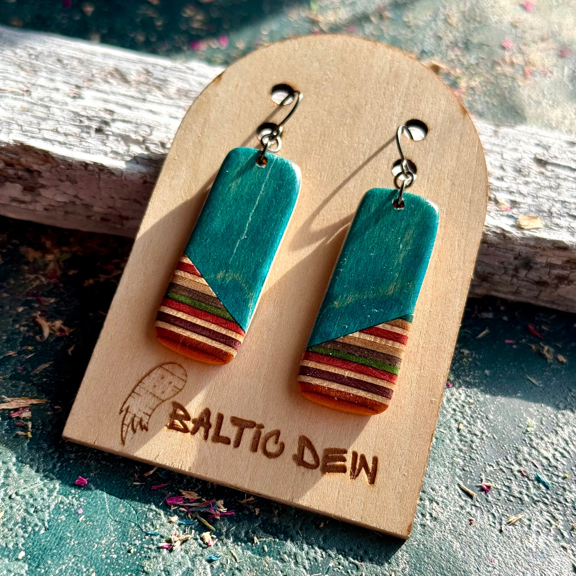 Turquoise recycled skateboard rectangle drop earrings displayed on a Baltic Dew wooden earring card.