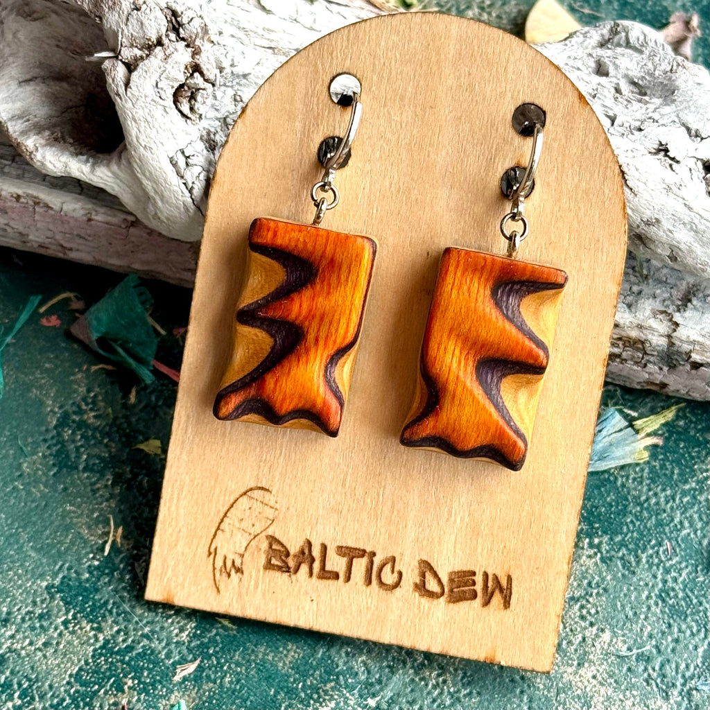 Bright orange carved skateboard wood earrings with dark purple waves through the layers