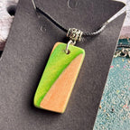 Green wooden pendant cut from recycled skateboard maple, split on the diagonal with bare wood.