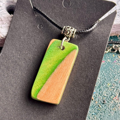 Green wooden pendant cut from recycled skateboard maple, split on the diagonal with bare wood.