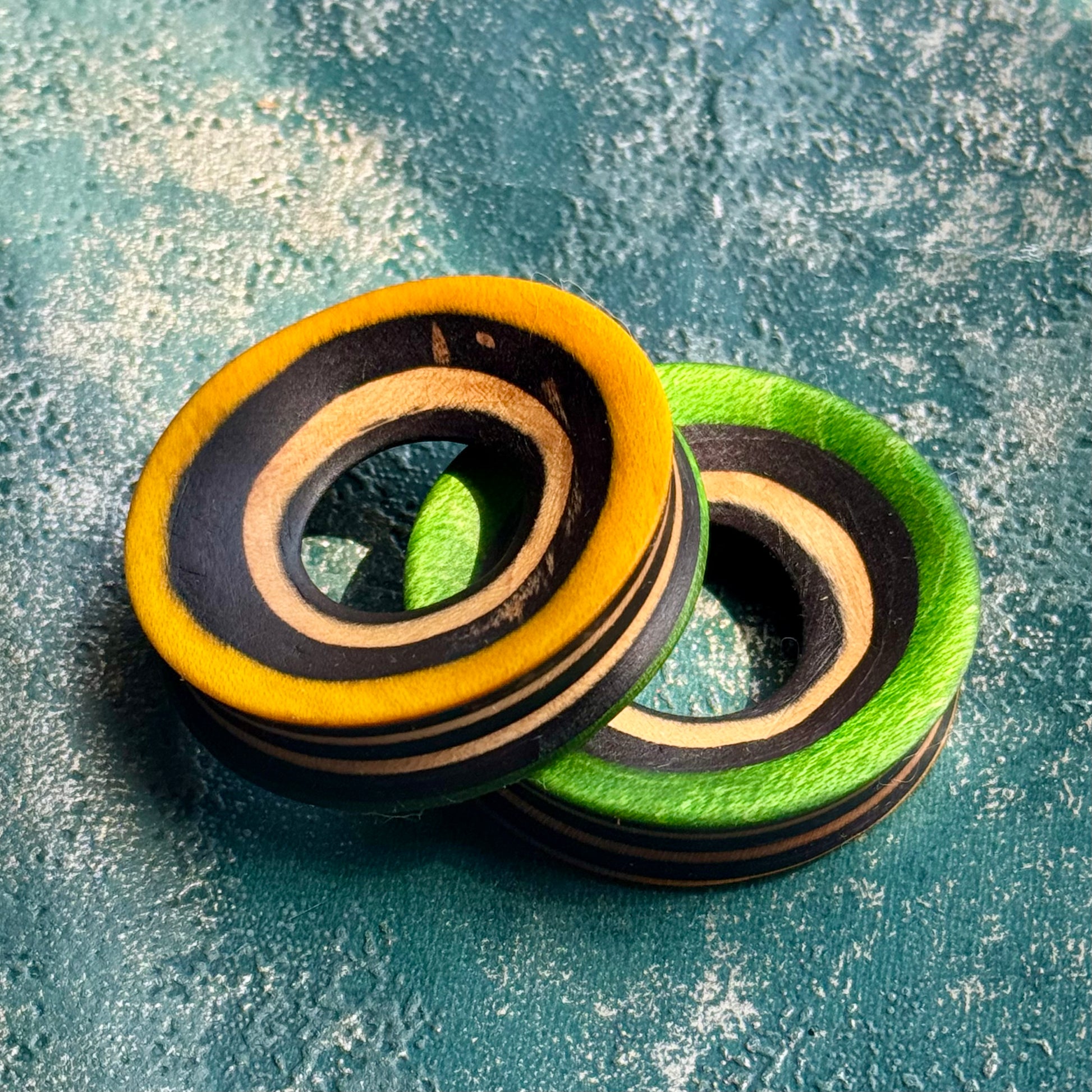 Orange and green wooden ear tunnels cut from a recycled skateboard, layered maple around the bore.