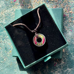 Skateboard bearing pendant necklace displayed in an open green jewellery box.