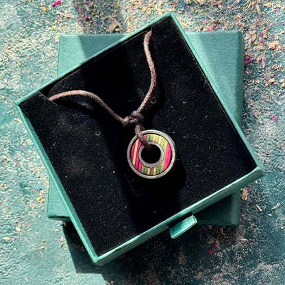 Skateboard bearing pendant necklace displayed in an open green jewellery box.