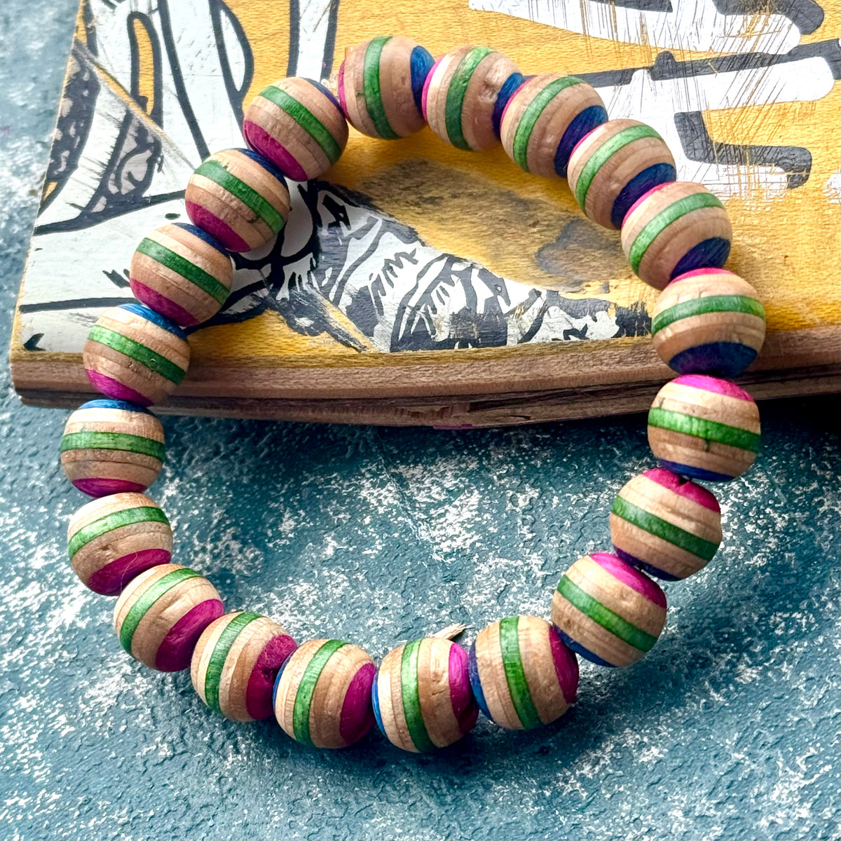 Pink and green recycled skateboard wood bead bracelet, with pink, green and dark blue layers on every bead.