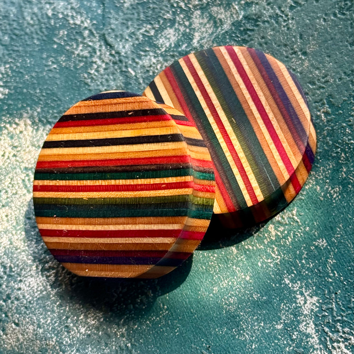 Pair of round plugs with fine skateboard maple stripes running across the face.