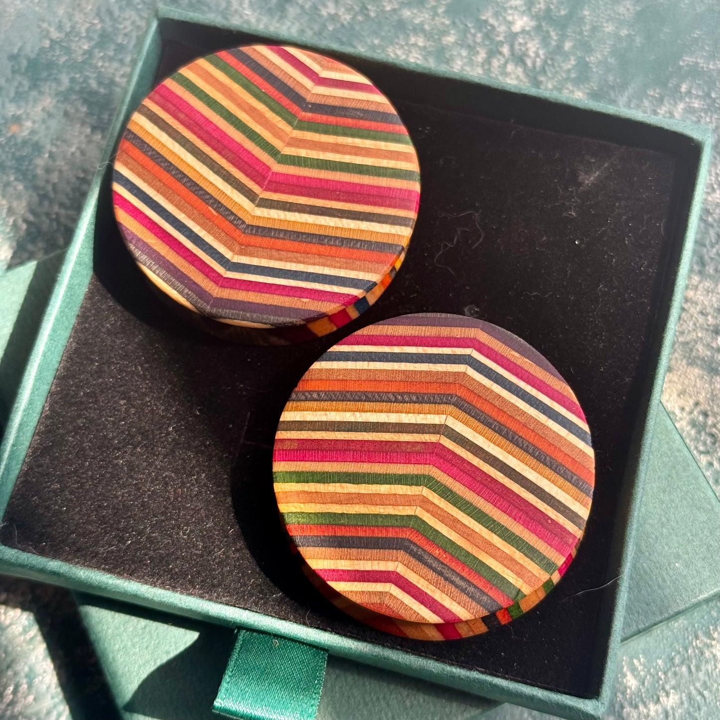 A pair of striped wooden ear plugs in a Baltic Dew gift box, ready to give.