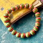 Close-up of red, green and teal layers on beads cut from a recycled skateboard deck, handmade by Baltic Dew.
