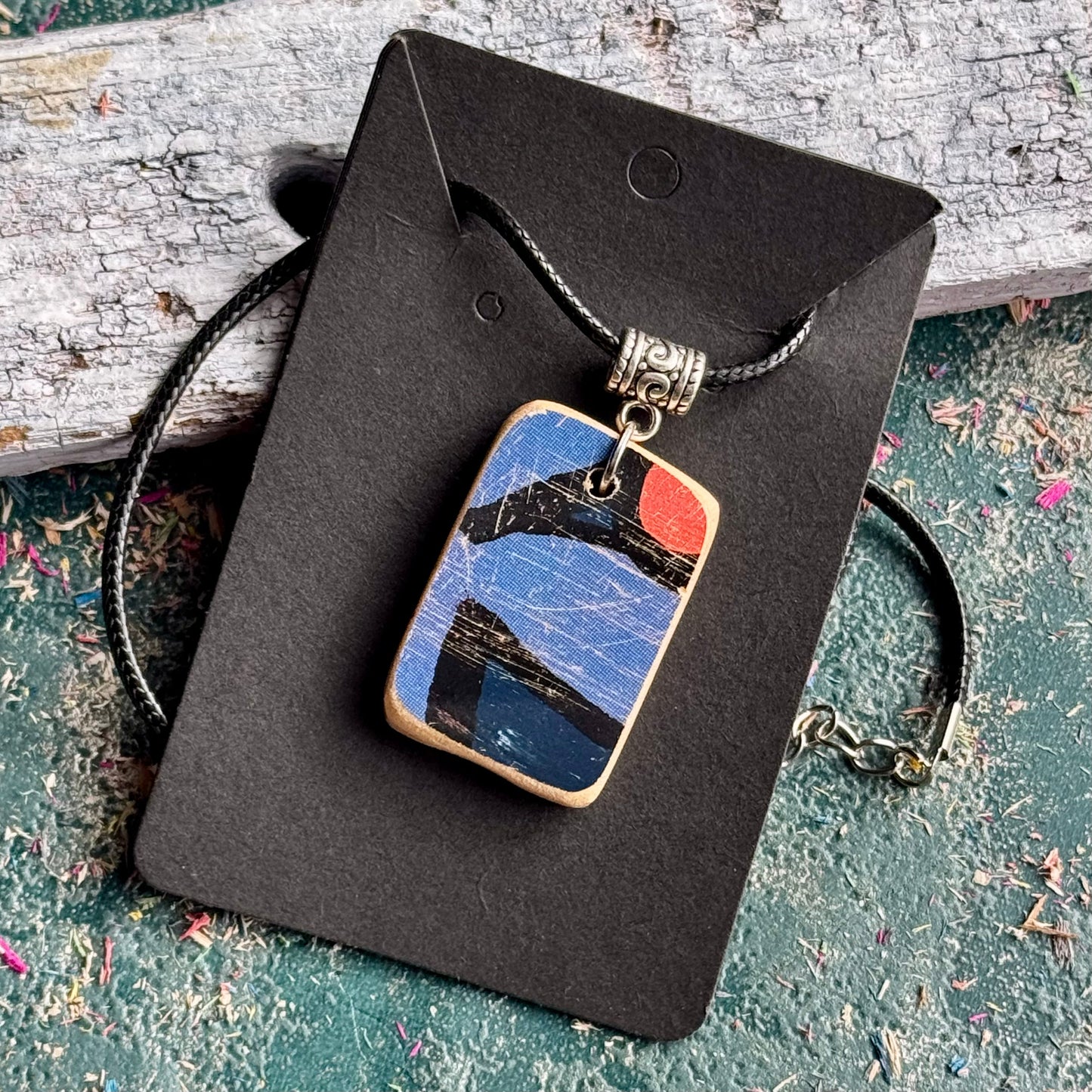 Blue and orange skateboard wood pendant on a black waxed cord, handmade by Baltic Dew.