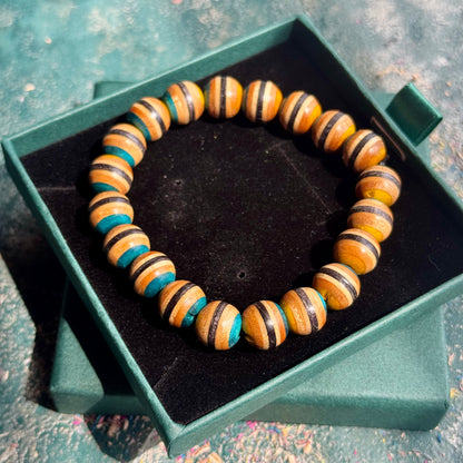 Yellow and Blue Skateboard Bracelet made of wooden beads with alternating yellow and blue stripes, displayed in a green jewelry box.