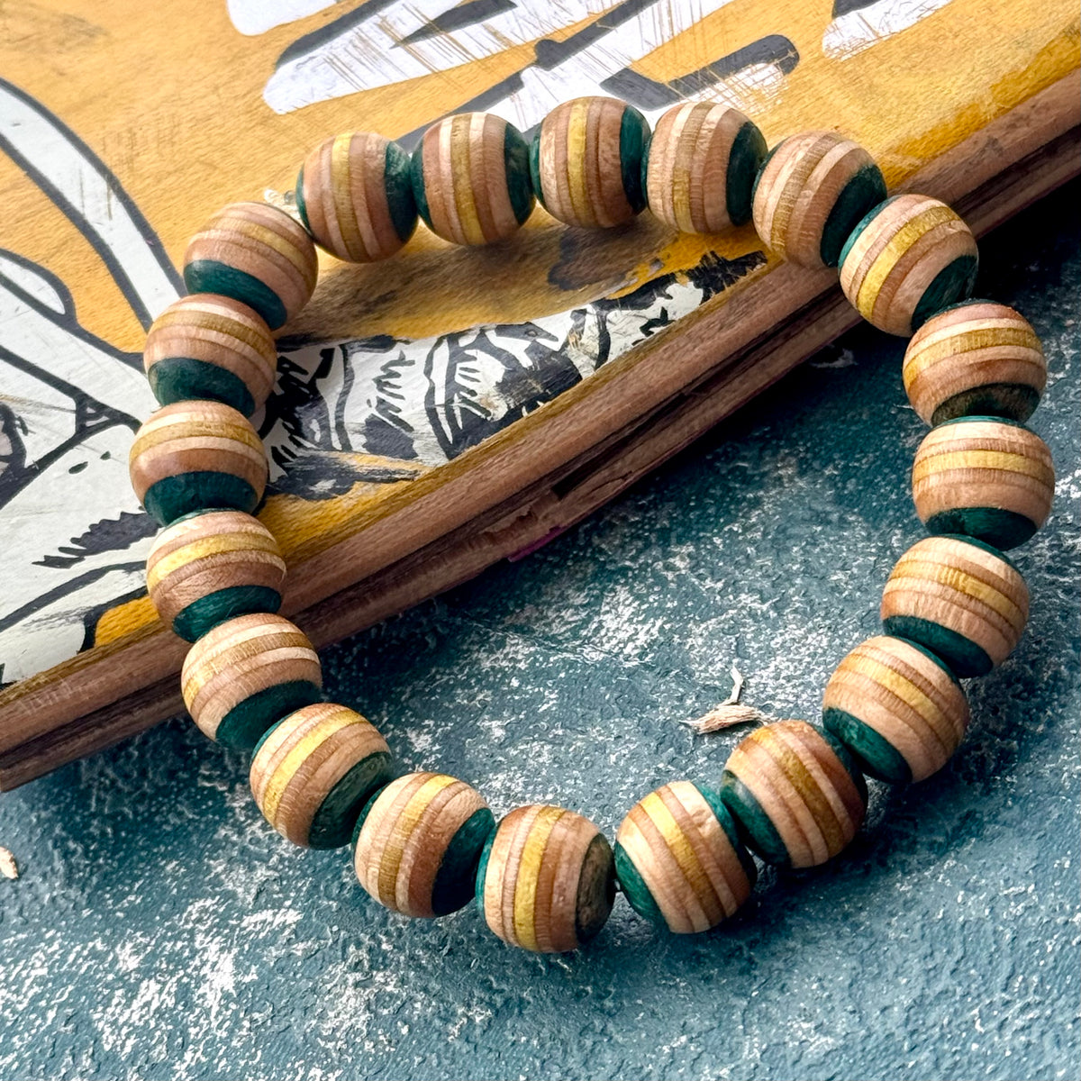 Light teal and yellow recycled skateboard wood bead bracelet, handmade by Baltic Dew.