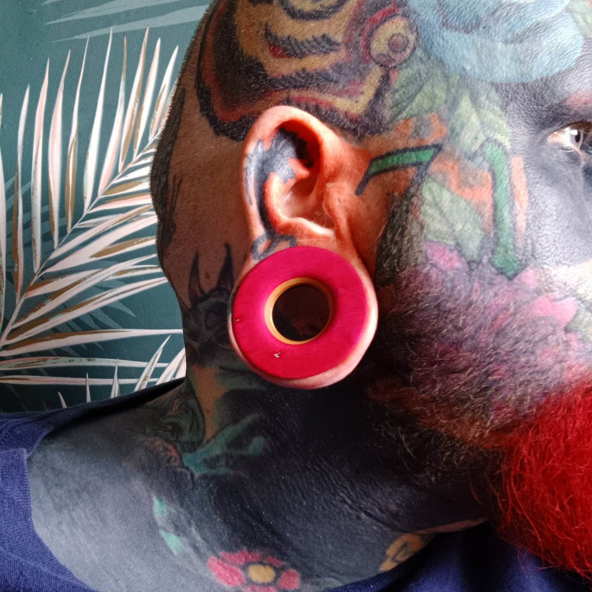 Large pink wooden ear tunnel worn in a heavily stretched lobe, handmade by Baltic Dew.