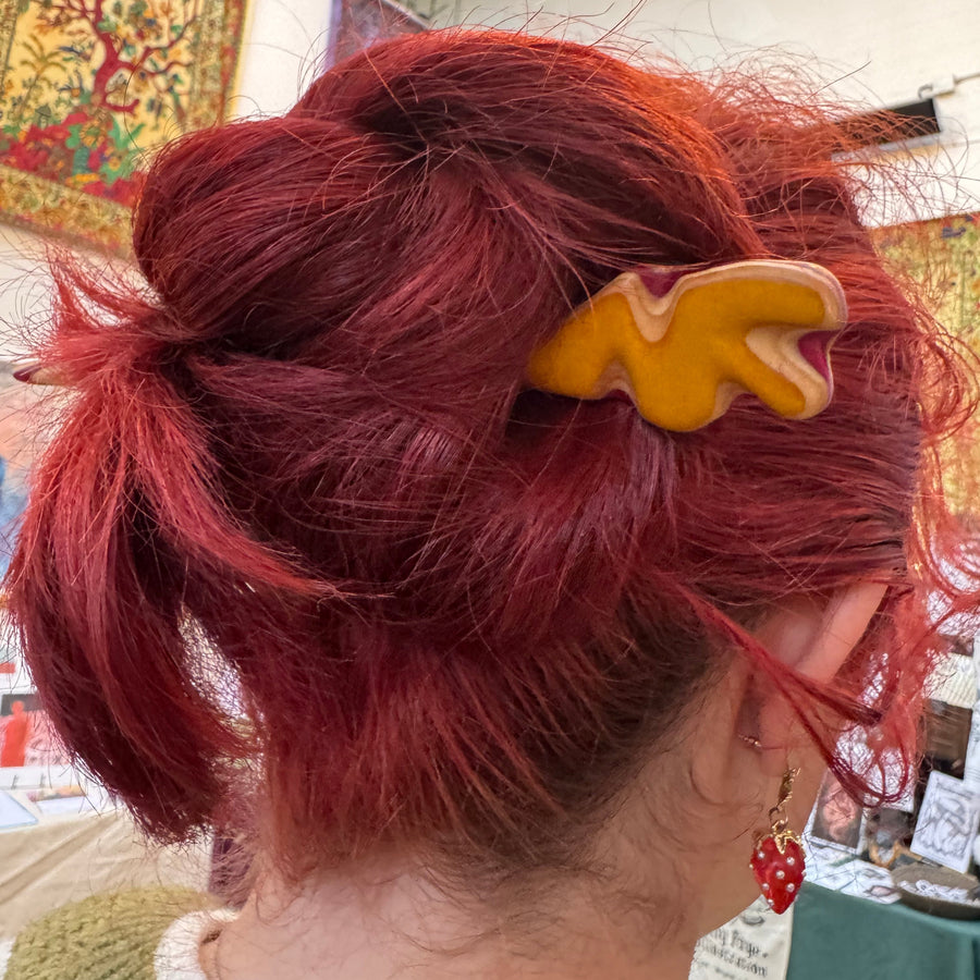 Yellow and red skateboard wood hair fork holding up a bun in red hair