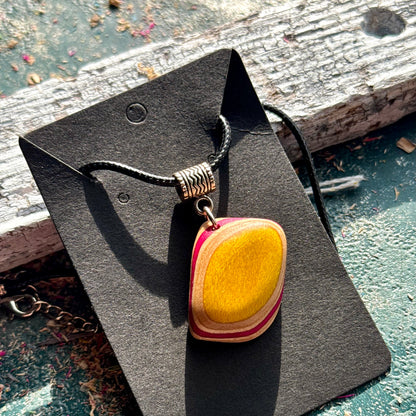 Domed skateboard wood pendant with a yellow centre and pink edge layers, handmade by Baltic Dew.