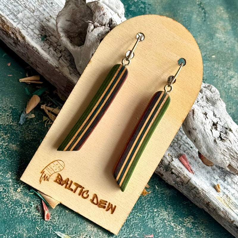 Green and dark striped recycled skateboard wood long drop earrings hanging on a wooden card