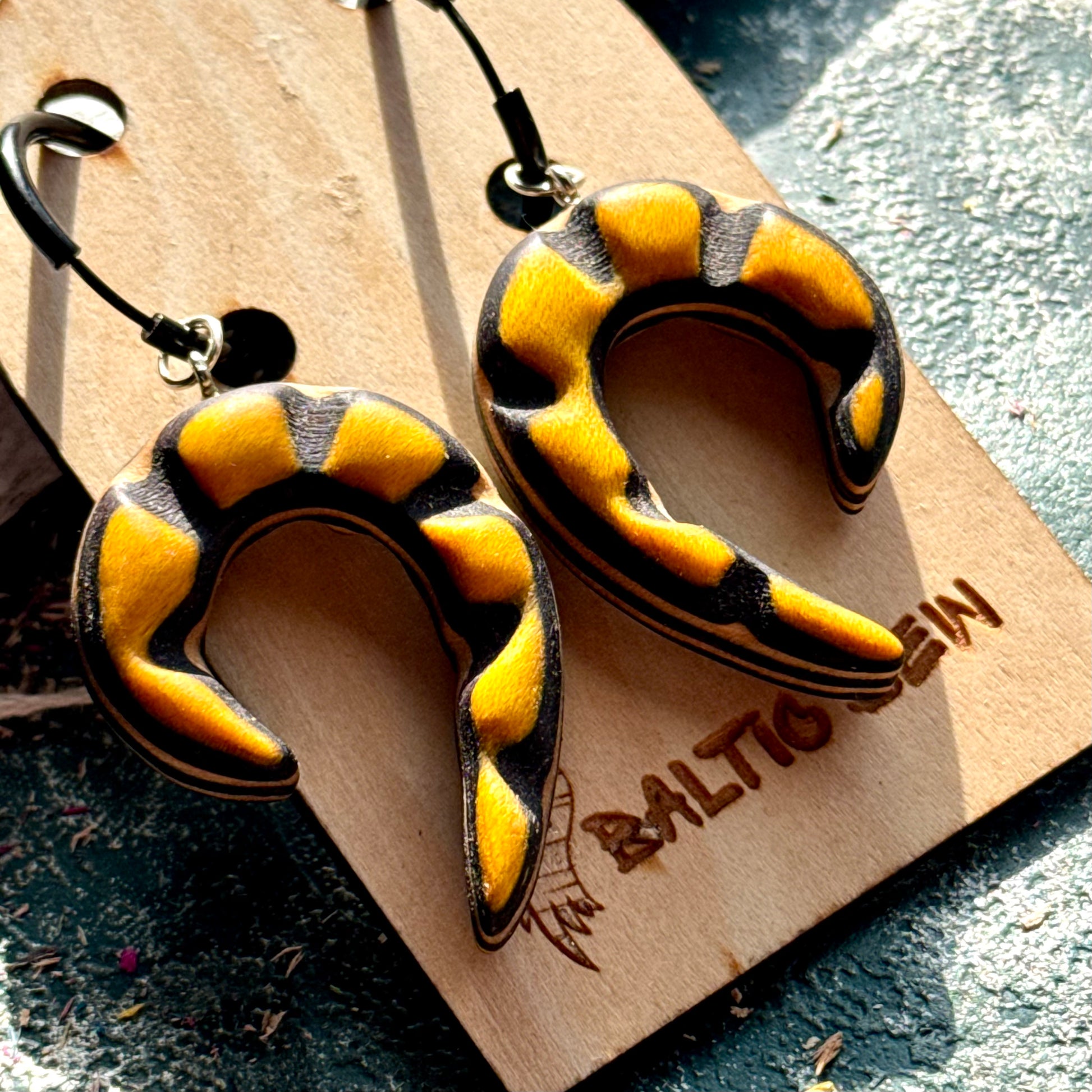 Yellow and black carved spiral earrings made from recycled skateboard maple on black hoops