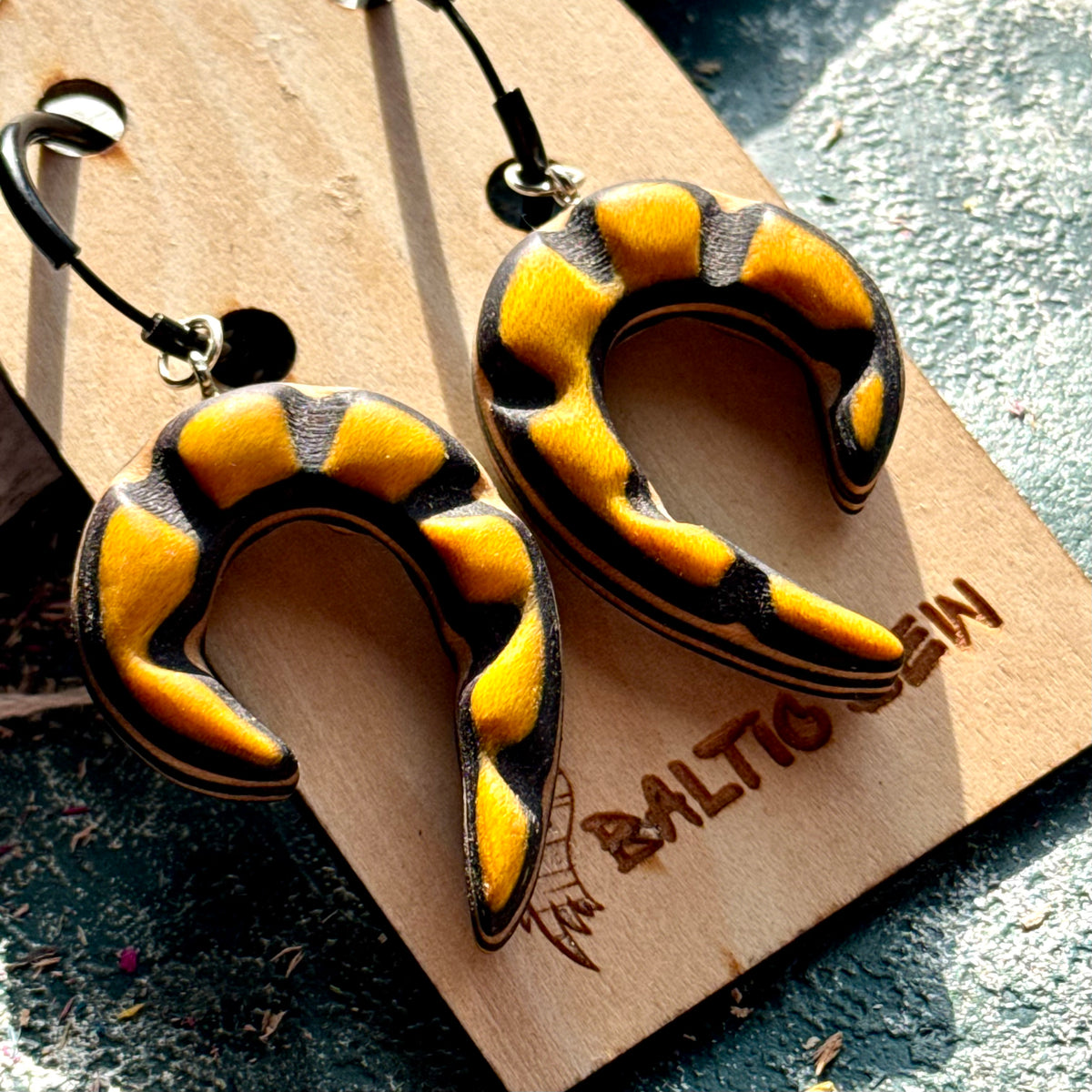 Yellow and black carved spiral earrings made from recycled skateboard maple on black hoops