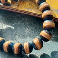 Blue and black striped skateboard maple beads in sunlight, bracelet leaning on a deck edge, handmade by Baltic Dew.