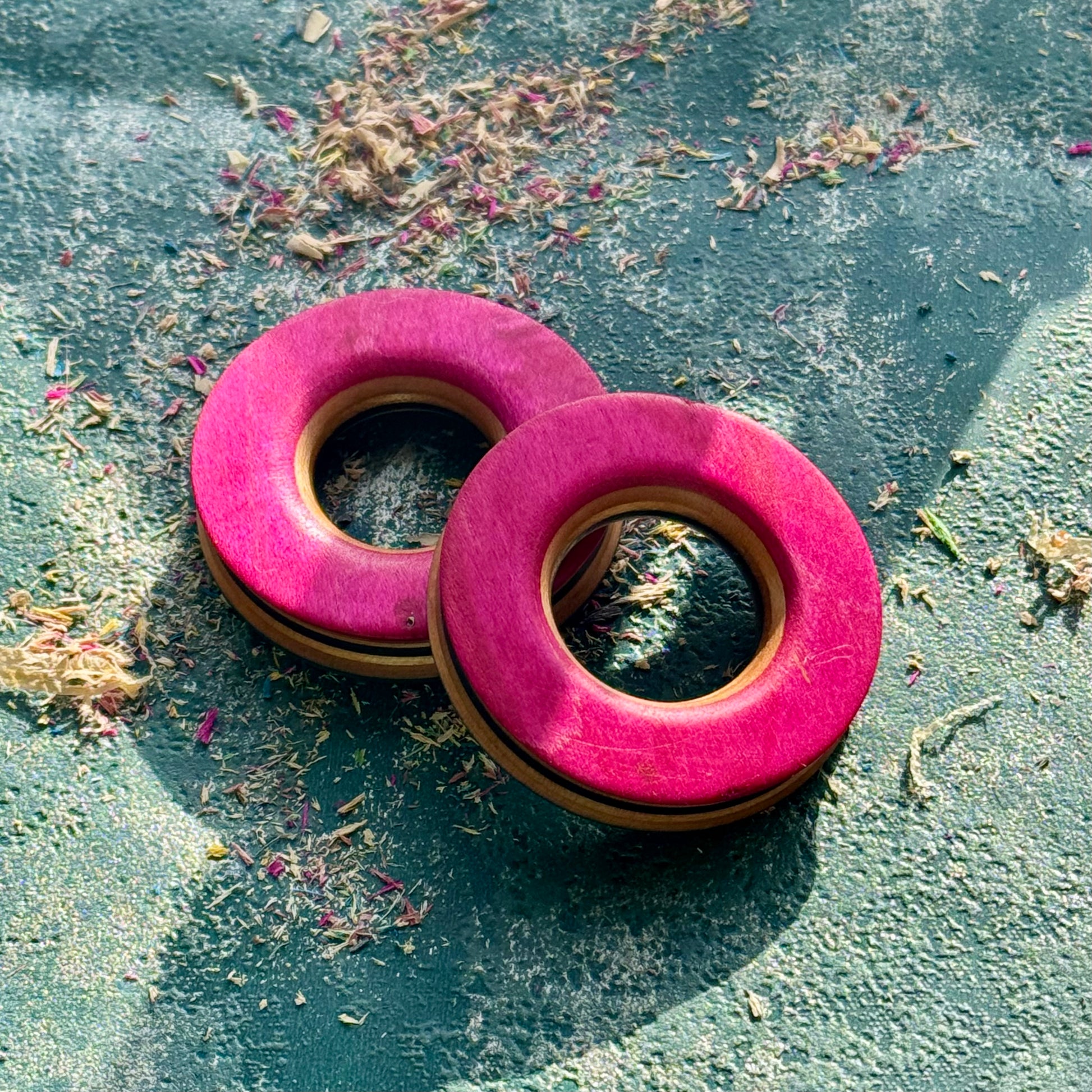 A matched pair of pink skateboard-wood tunnels, coloured maple stacked around the opening.