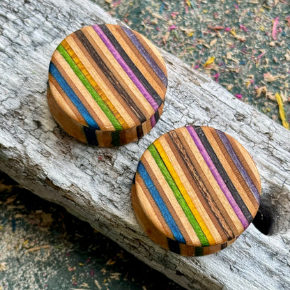 Wooden ear plugs with blue, purple, orange and green stripes across the face, cut from a recycled skateboard.