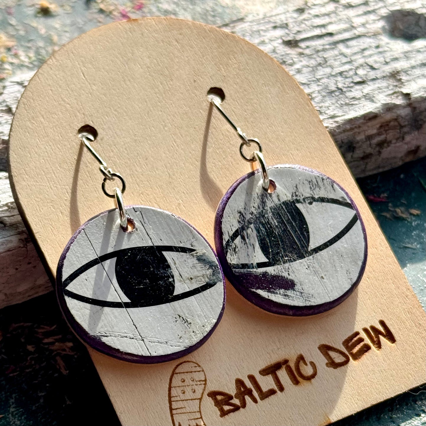 Black and white recycled skateboard wood drop earrings showing cat eyes from the deck graphic